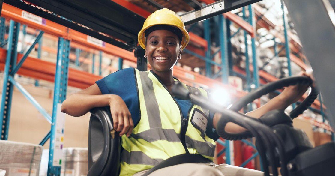 a worker smiling happily riding a forklift