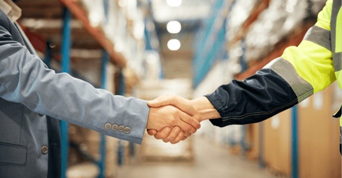 a firm handshake from a veteran and a worker in a logistic warehouse