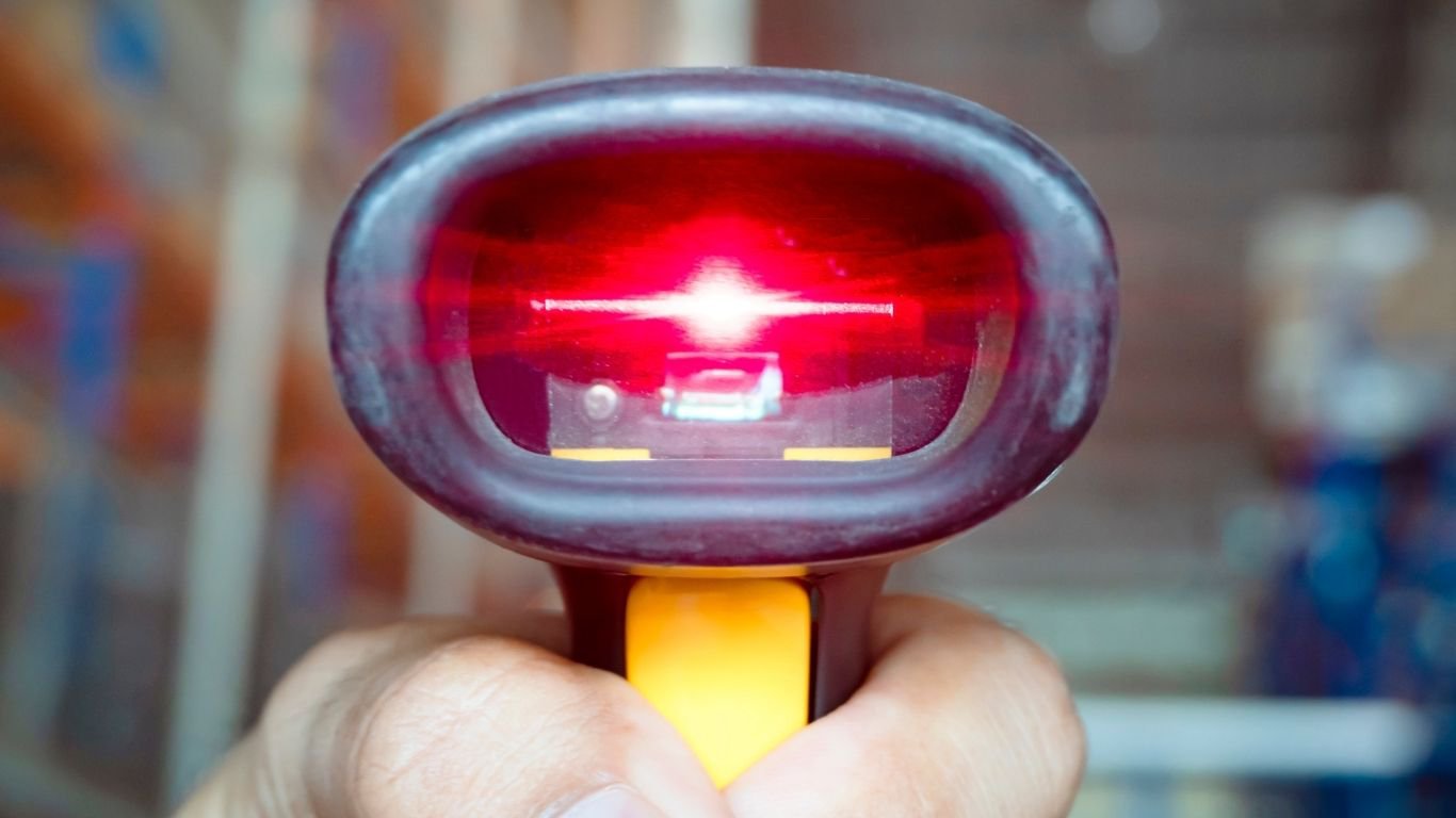 A close-up of a hand holding one of the durable scanners used in warehouses.