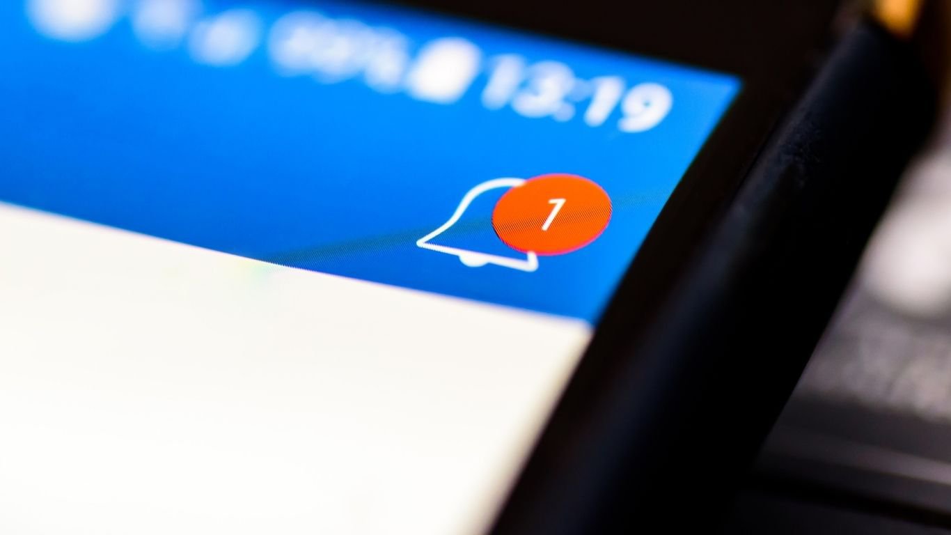 A smartphone screen displaying a notification bell icon from a stock alerts app.