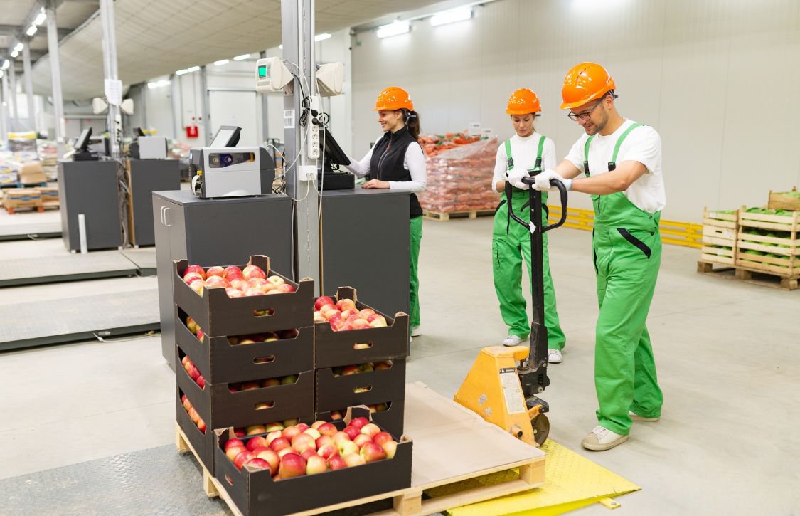 warehouse workers moving a pallet of apples